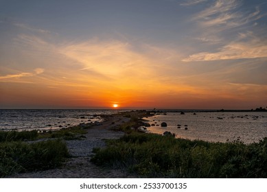 Serene sunset over a rocky coastline with gentle waves and a vibrant sky, capturing the beauty of nature's evening colors. - Powered by Shutterstock