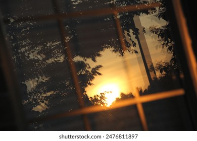 A serene sunset reflected through a window, showcasing the rule of thirds and capturing the peaceful evening light. Perfect for themes of tranquility and reflection. - Powered by Shutterstock