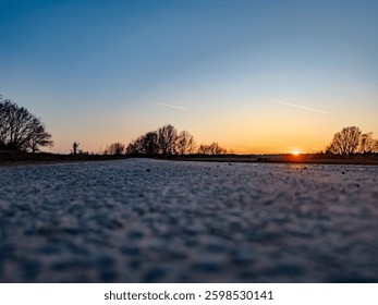 A serene and tranquil sunset casting warm hues over a deserted, peaceful road, ideal for nature and travel themes