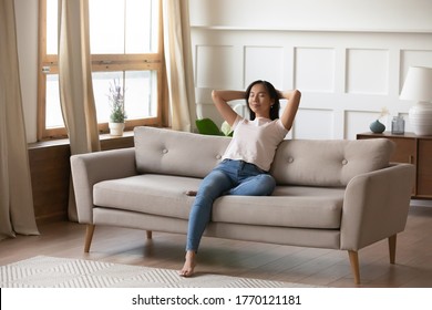 Serene tranquil young vietnamese biracial ethnicity woman folded hands behind head, resting with closed eyes on comfortable orthopedic couch, enjoying stress free weekend lazy leisure time at home. - Shutterstock ID 1770121181