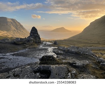 A serene valley at sunset with a stone cairn in the foreground, rolling hills, and a calm ocean in the distance. Warm golden light and dramatic skies create a tranquil and picturesque scene. - Powered by Shutterstock