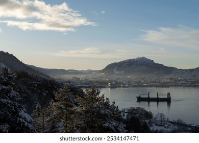 A serene view of Bergen wrapped in morning mist, with only the peak of Løvstakken mountain peeking through the clouds. The calm fjord reflects the soft light of early dawn - Powered by Shutterstock