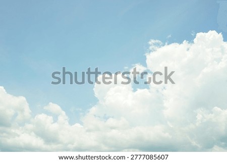 A serene view of bright white cumulus clouds drifting across a clear, pale blue sky, capturing the essence of a peaceful tropical morning.
