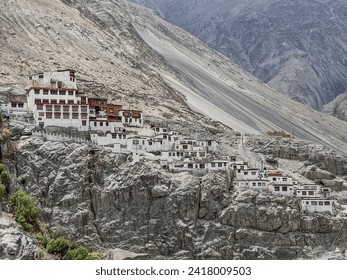 A serene view of a cliffside Buddhist monastery in the Himalayas, integrating historical architecture with the raw beauty of the Nubra Valley's rugged landscape. - Powered by Shutterstock