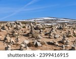 A serene view of hand-crafted stone pyramids by visitors, symbolizing the Arctic Circle, near the Arctic Circle Center in Rana, Nordland, Norway