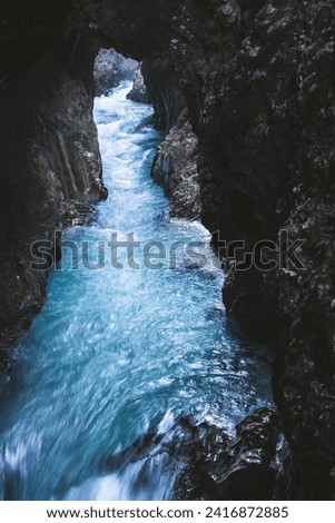 A serene view of a narrow turquoise river flowing through a rocky gorge