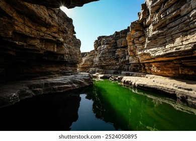 A serene view of a rocky canyon with green water under a clear blue sky. - Powered by Shutterstock