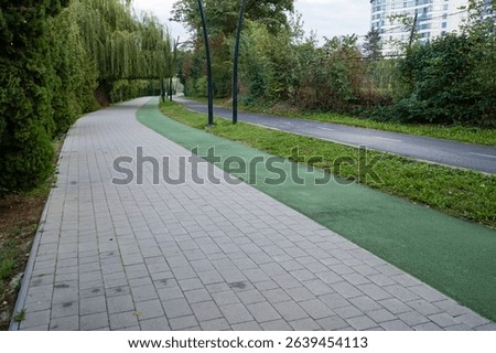 A serene walking path meanders through a lush urban landscape, surrounded by trees, as morning light filters through, inviting residents to enjoy nature and exercise.