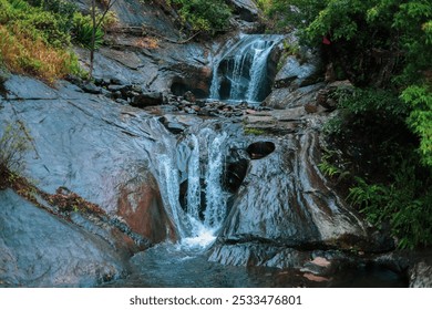 Serene Waterfall Flowing Over Rocky Terrain in a Lush Forest Setting - Powered by Shutterstock