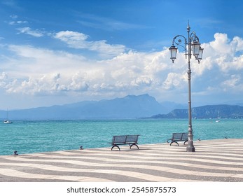 Serene waterfront promenade with a vintage streetlamp, benches, and turquoise lake under a bright blue sky. A peaceful Mediterranean scene. - Powered by Shutterstock