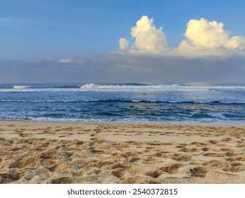 Serene Watu Kodok beach scene with clear blue sky and fluffy white clouds. Ocean calm with gentle waves rolling towards the shore. Sandy beach pristine with footprints leading towards water. - Powered by Shutterstock