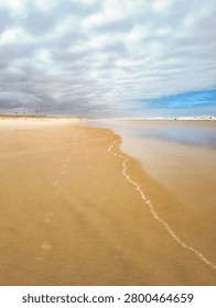 Serene wideangle view of a tranquil empty sandy beach under a cloudy sky. Nobody is here, evoking solitude, calm, and peaceful reflection in nature. Perfect for travel and wellness.