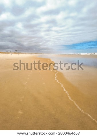 Serene wideangle view of a tranquil empty sandy beach under a cloudy sky. Nobody is here, evoking solitude, calm, and peaceful reflection in nature. Perfect for travel and wellness.