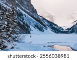 A serene winter landscape at Lake Louise surrounded by snow-covered pine trees and rugged mountain peaks