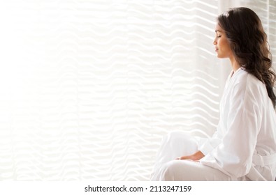 Serene Woman In Bathrobe Meditating At Sunny Window