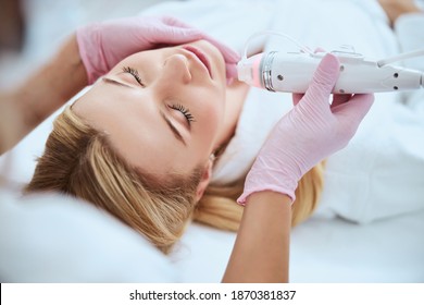 Serene woman being treated by a dermatologist in a beauty salon using the fractional microneedle machine
