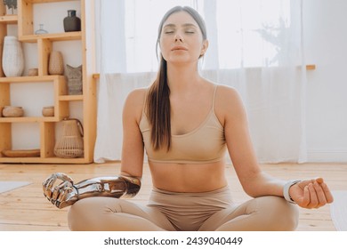 Serene woman meditating in a yoga pose with a prosthetic robotic arm, demonstrating harmony between humanity and technology in a tranquil home environment.Meditative Pose with Bionic Arm - Powered by Shutterstock