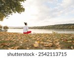 Serene woman practicing meditating by the riverside, embracing nature and well-being. Stress relief.