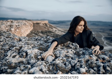 serene woman sitting on rocky ledge with arms outstretched in peaceful meditation - Powered by Shutterstock