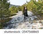 serene woman strolling through lush pine forest with sunlight filtering through the trees