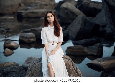 Serene woman in white dress resting on coastal rock formation by the ocean - Powered by Shutterstock