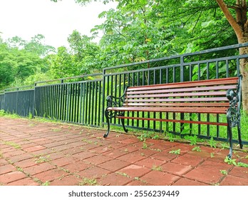 A serene wooden bench by the lush green foliage, offering a peaceful retreat amidst nature’s embrace under a tranquil sky. - Powered by Shutterstock