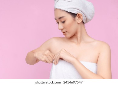 Serene young Asian lady wrapped in a white towel, with a towel turban against a soft pink background. - Powered by Shutterstock