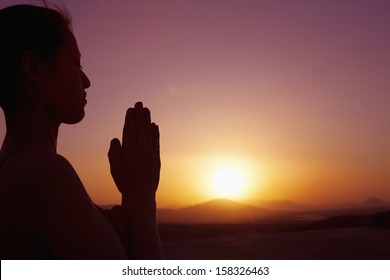 Serene young woman with hands together in prayer pose