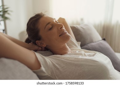 Serene young woman lying on the sofa at home and relaxing, she is smiling and resting with eyes closed - Shutterstock ID 1758598133
