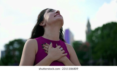 Serene young woman putting hands in chest gazing upwards at sky. Happy person feeling peace and tranquility - Shutterstock ID 2311186809