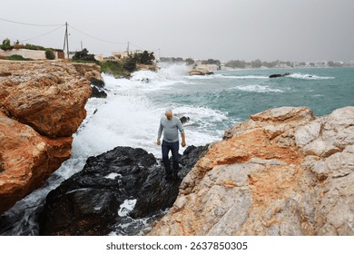 Serenity and strength man stands firm on rocks facing the crashing waves.