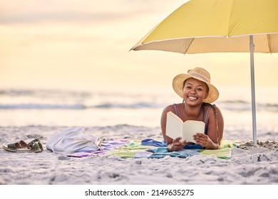 Serenity That Speaks Volumes. Portrait Of A Beautiful Young Woman Relaxing With A Book At The Beach.