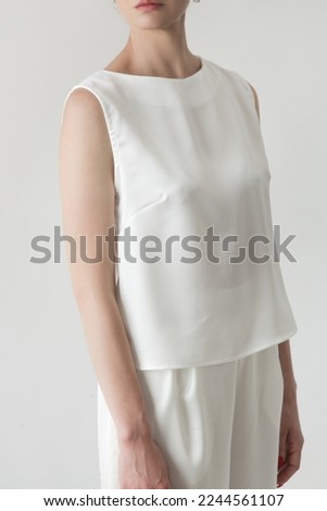 Serie of studio photos of young female model in all white silk outfit, sleeveless blouse and wide legs trousers