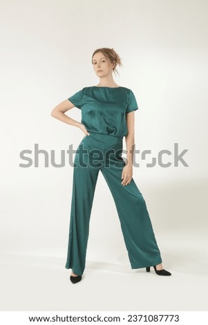 Serie of studio photos of young female model in green silk outfit.

