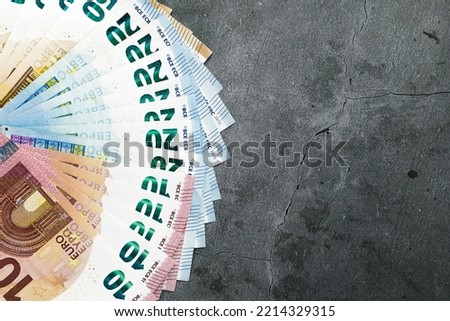 Series of euro banknotes arranged in a fan shape on a dark gray background. Concept of Europe, monetary policy, public debt, inflation, monetary crisis, European economy.