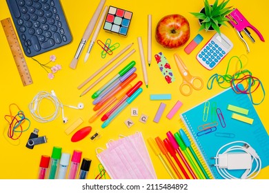 Series Of Stationery Items For Kids, Colored Pens, Labels, Paper Clips, Masks On Yellow Background, Back To School Concept, Flat Lay