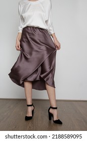 Series Of Studio Photos Of Young Female Model Wearing White Silk Satin Batwing Short Sleeve Blouse With Mocha Color Midi Skirt