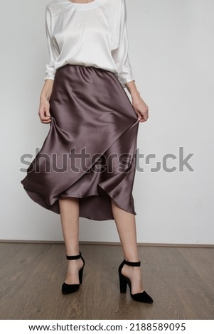 Series of studio photos of young female model wearing white silk satin batwing short sleeve blouse with mocha color midi skirt