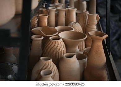 A series of vases, cups, bowls and containers in raw clay, in brown, beige, sand, grey colors, before being fired in a kiln by the artisan in his workshop. Dai minority in Yunnan, China. - Powered by Shutterstock