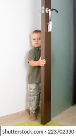 Serious 2-year boy handling a door