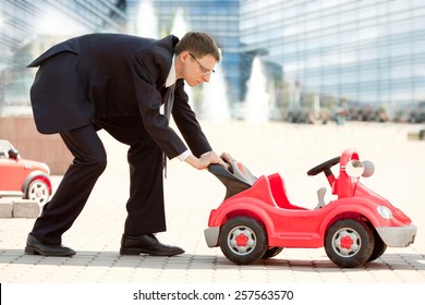 Serious Adult Businessman With The Little Red Toy Car