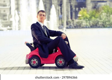 Serious Adult Businessman With The Little Red Toy Car