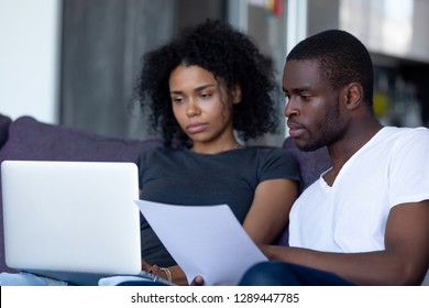 Serious African American Couple Reading Document Letter Pay Domestic Bills Checking Bank Account Online On Laptop At Home, Black Family Holding Paper Planning Budget Money Expenses With Computer App