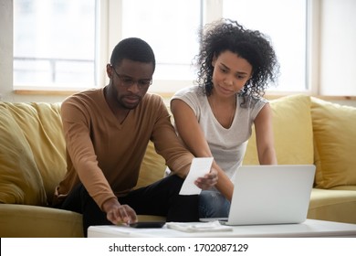 Serious African American Couple Using Calculator And Laptop For Calaulating Finance. Diverse Upset Man And Woman Taxing, Accounting With Check Credit Analytic For Mortgage Payment.