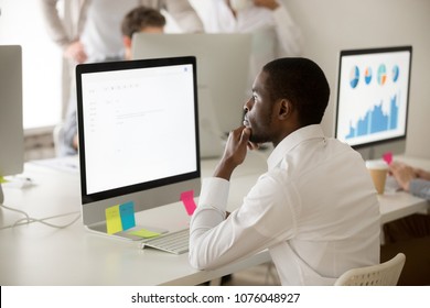 Serious African American Employee Thinking Over Business Email Working On Computer In Office, Focused Puzzled Black Manager Looking At Screen Reading Or Writing Electronic Letter To Corporate Client