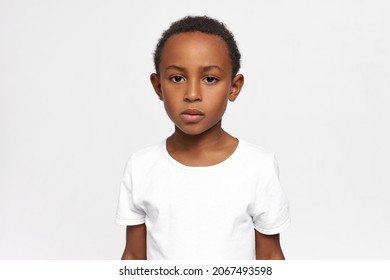 Serious African American Kid, Having Focused And Concentrated Face, Looking At Camera With Sadness, Worry And Melancholy In His Big Deep Brown Eyes. Kids And Their Attitude, Feelings, Emotions