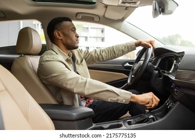 Serious african american man driving a car, shifting gears