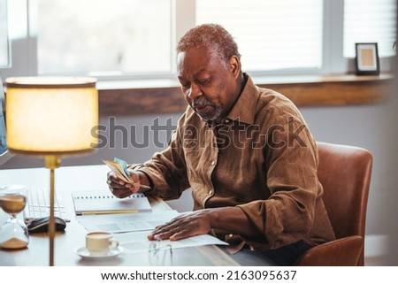 Serious African American man  in living room manage budget received invoice analyzes month expenses feels concerned about public utility debt, check read loan documents concept