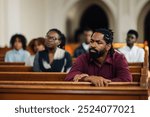 Serious african american man sits in a church pew, listening to a pastor