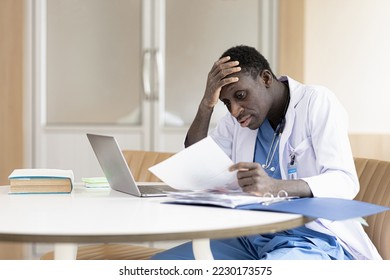 Serious African American manager in stylish glasses reading corporate document with note, sales report, boss order, doing paperwork. Legal expert checking document at workplace with laptop - Powered by Shutterstock